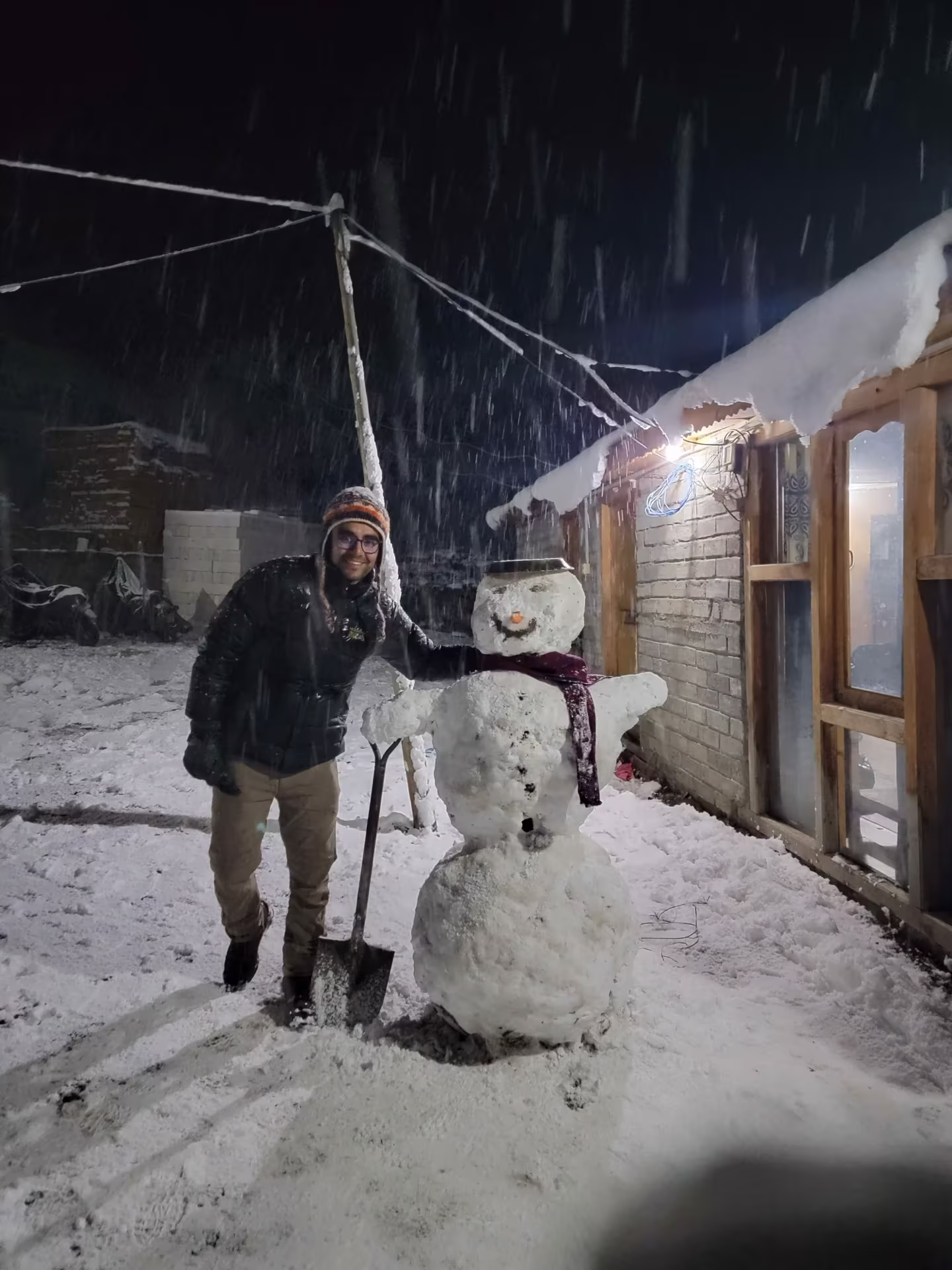 A traveler beside a snowman they built on the trail