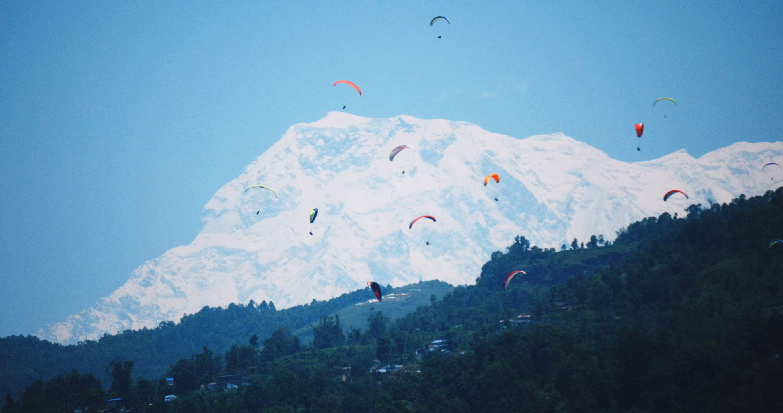 Paragliders flying with snowy Himalayan peaks in the background