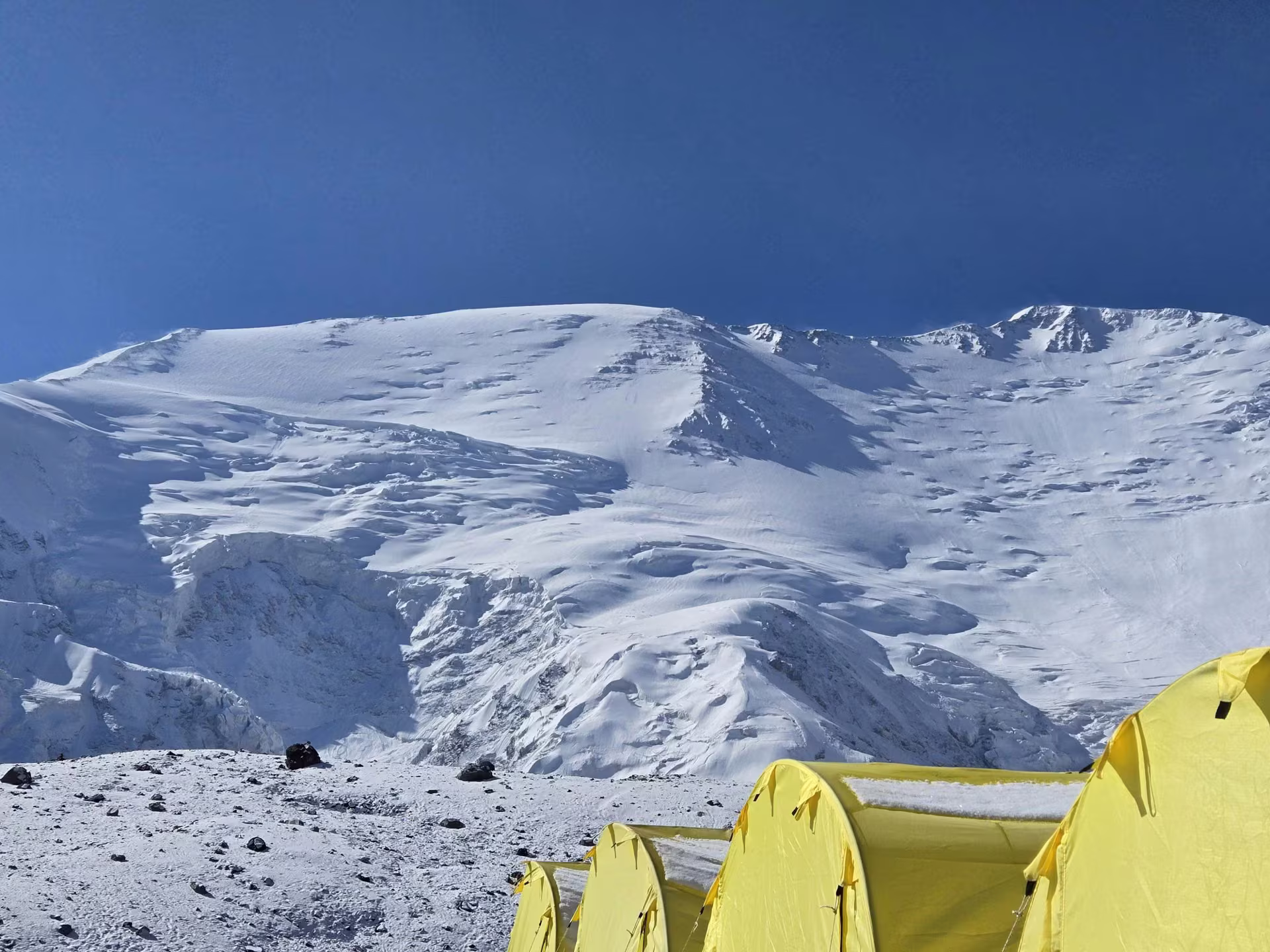Expedition tents pitched in the mountains beneath a snowy peak