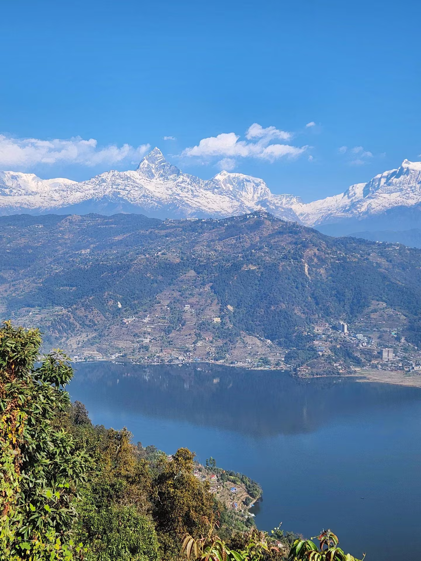 A lake framed by green hills and snowy peaks