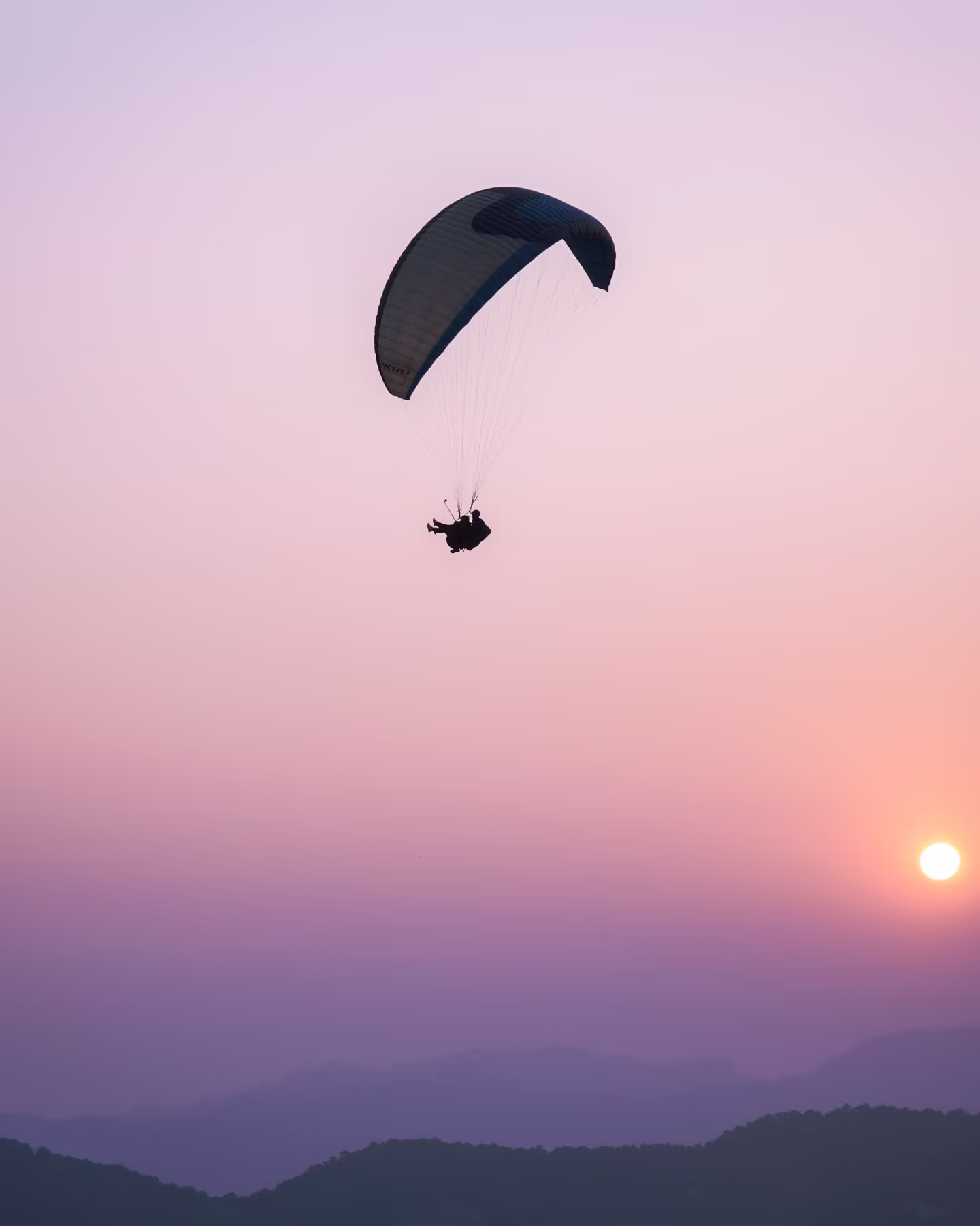 Paraglider silhouettes against a glowing evening sky