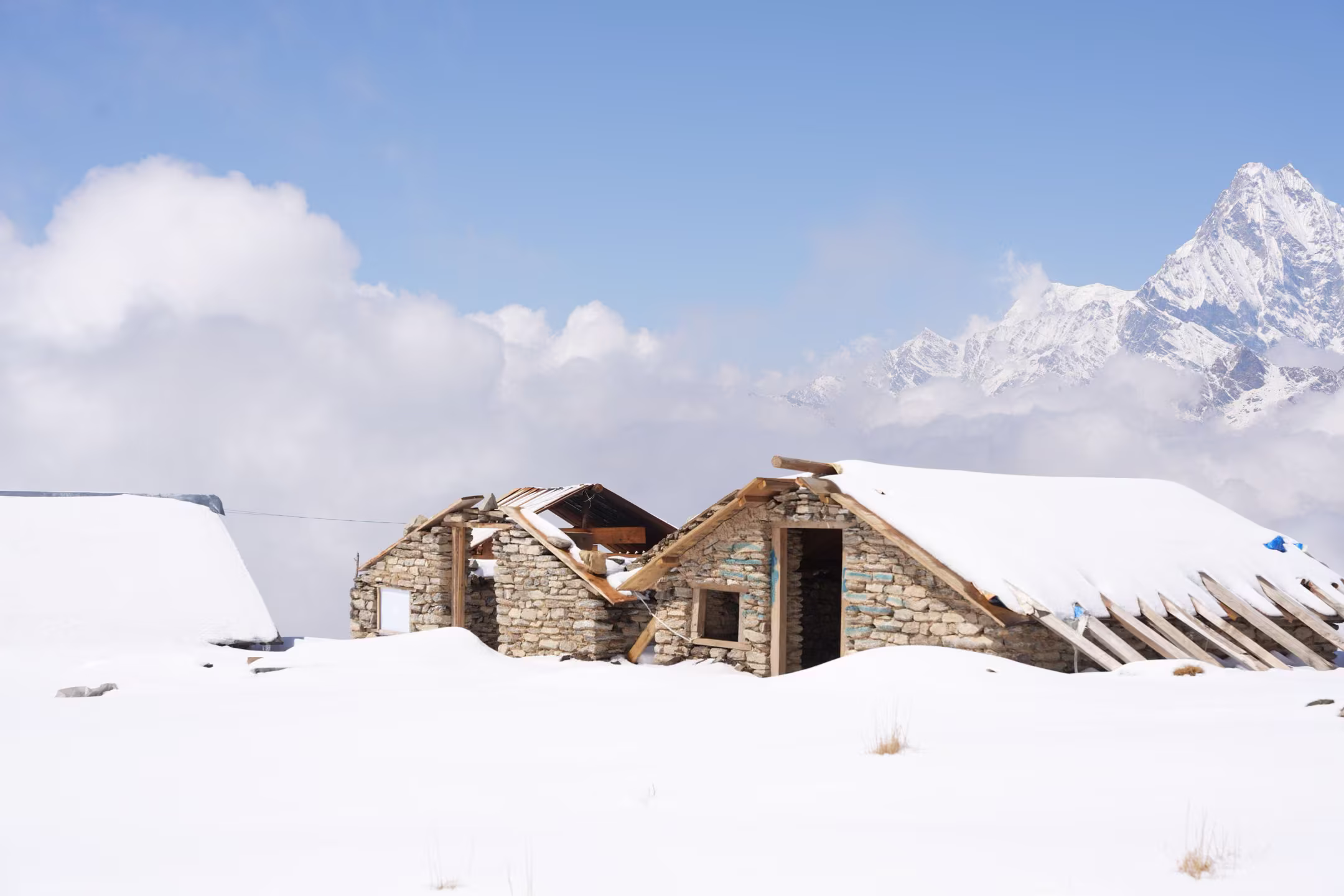 Three snow-covered cottages with mountains behind