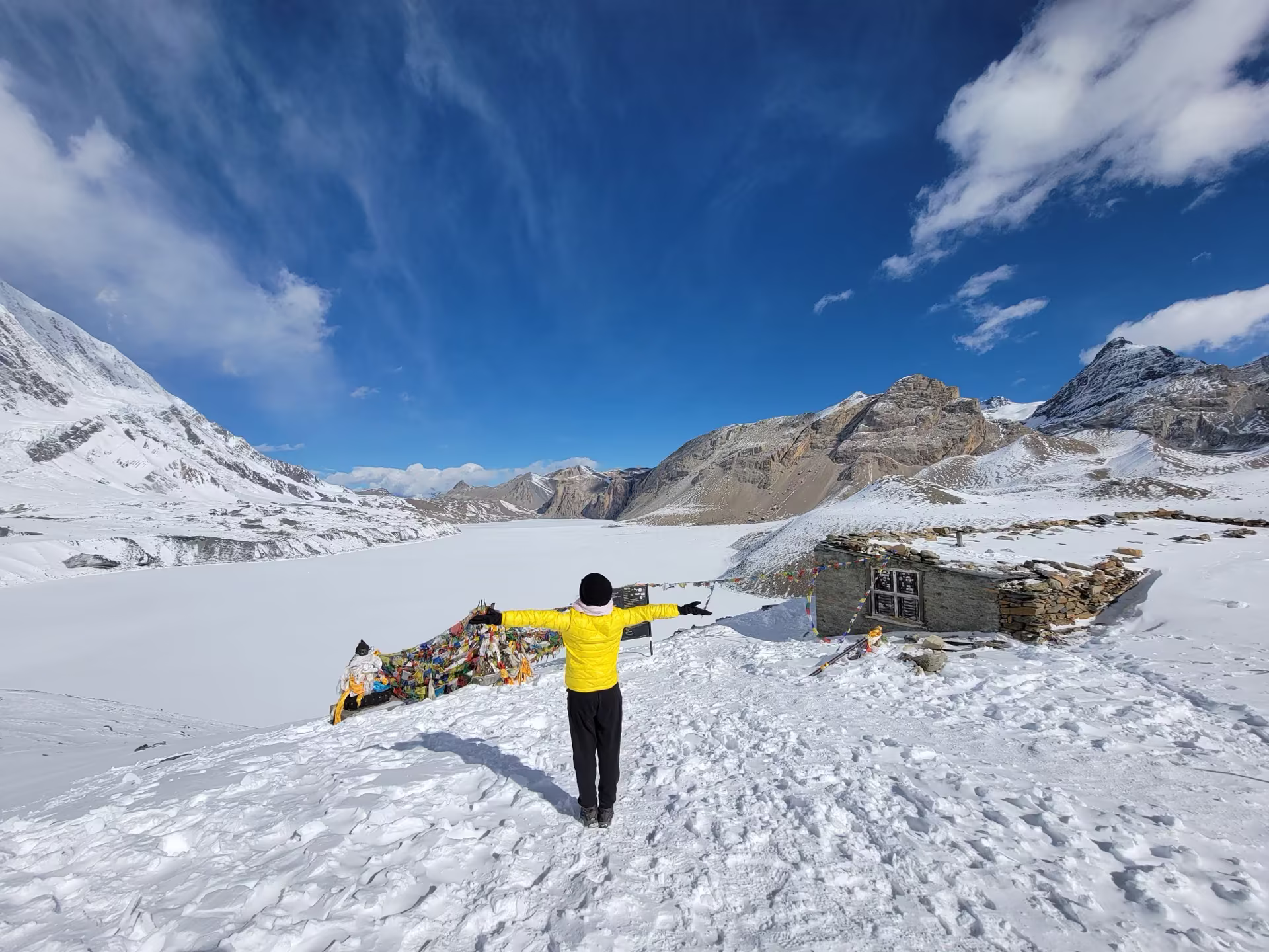 A trekker standing beside a frozen alpine lake