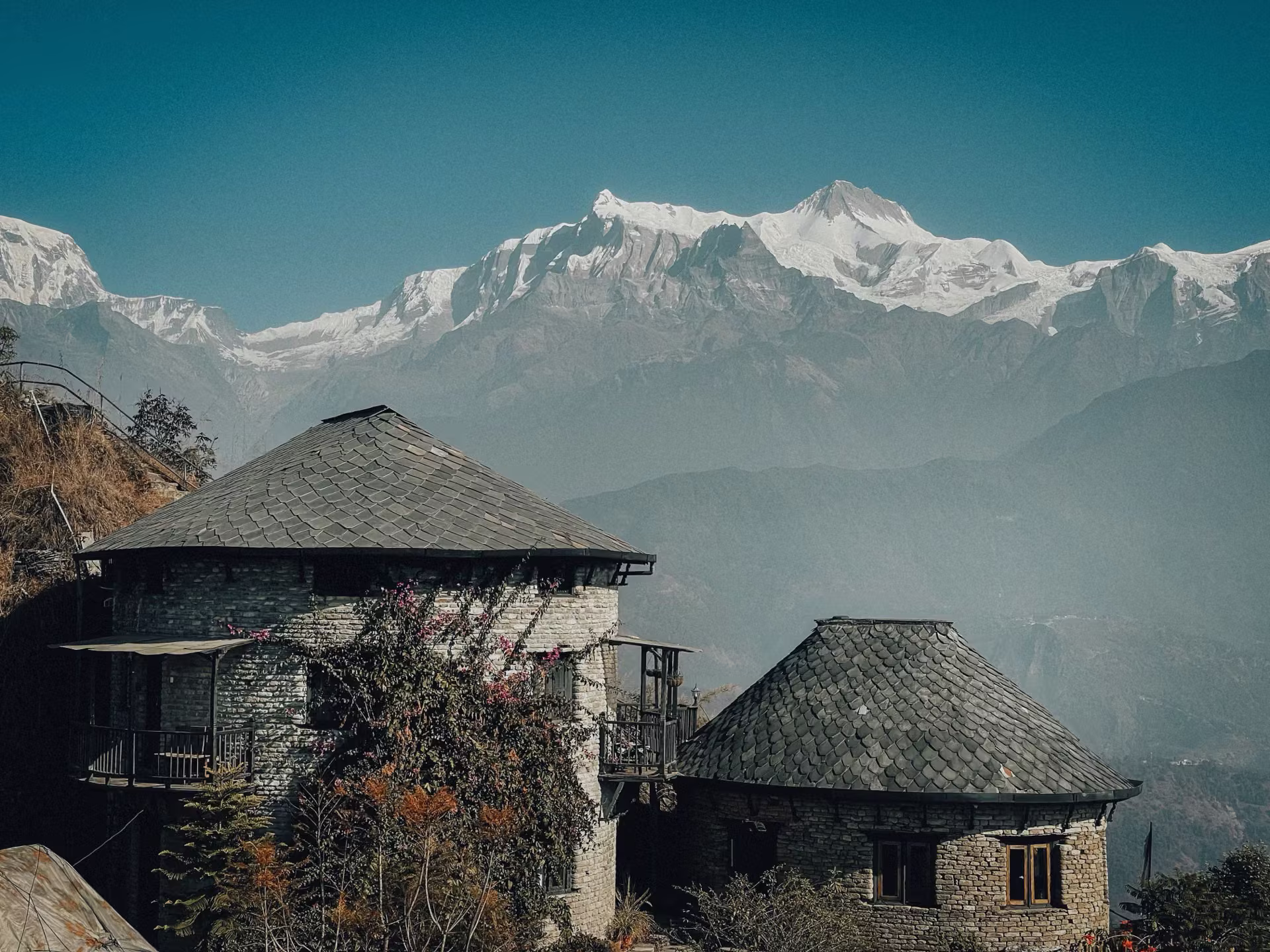Two cottages beneath a snowy Himalayan peak